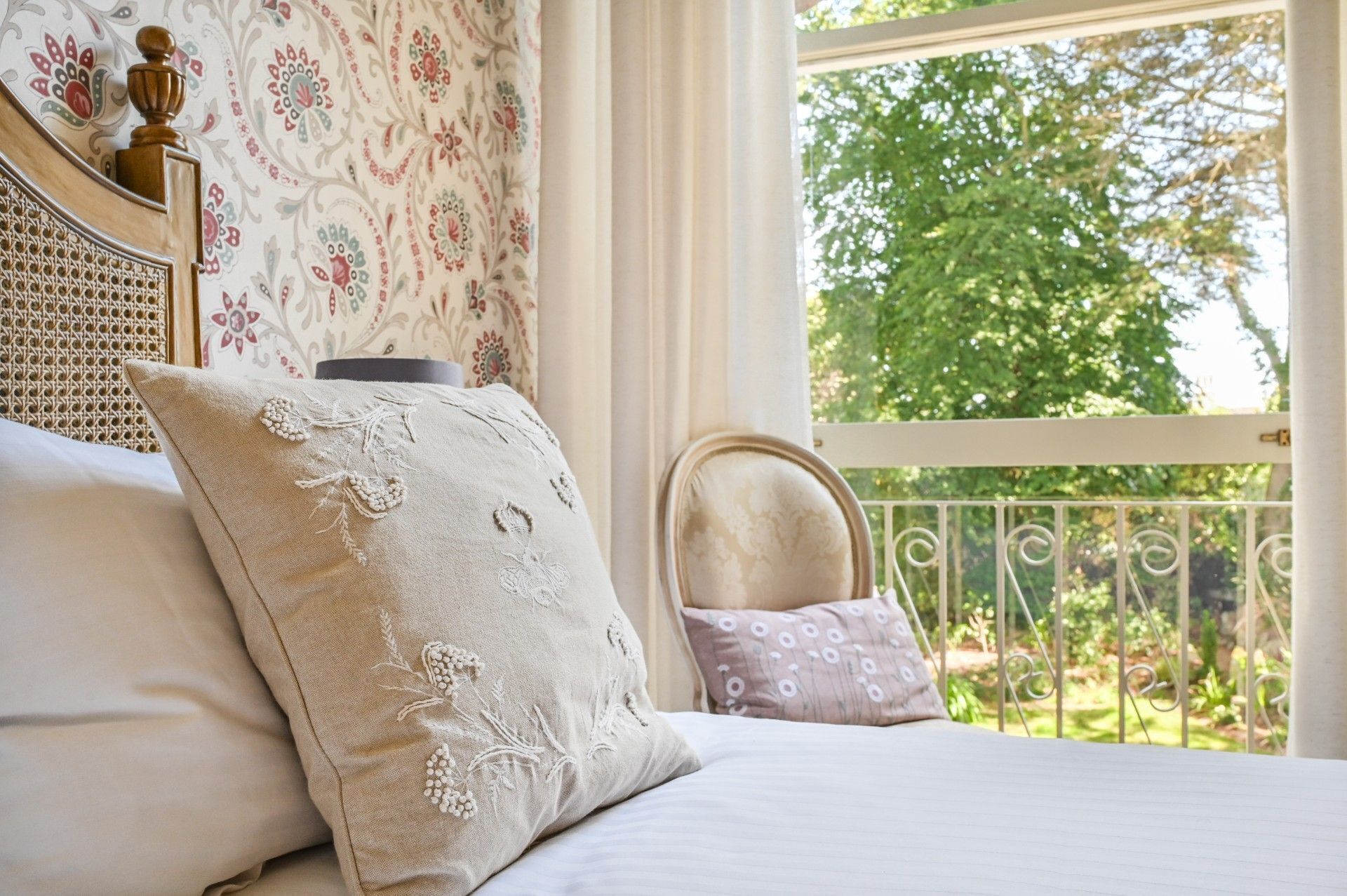 Ein Schlafzimmer mit einem Bett, einem Fenster mit Blick auf Grünflächen und einer Wand mit Muster.