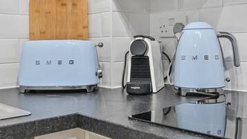 A kitchen with two light blue Smeg appliances, a wooden cutting board, and white tiled walls.