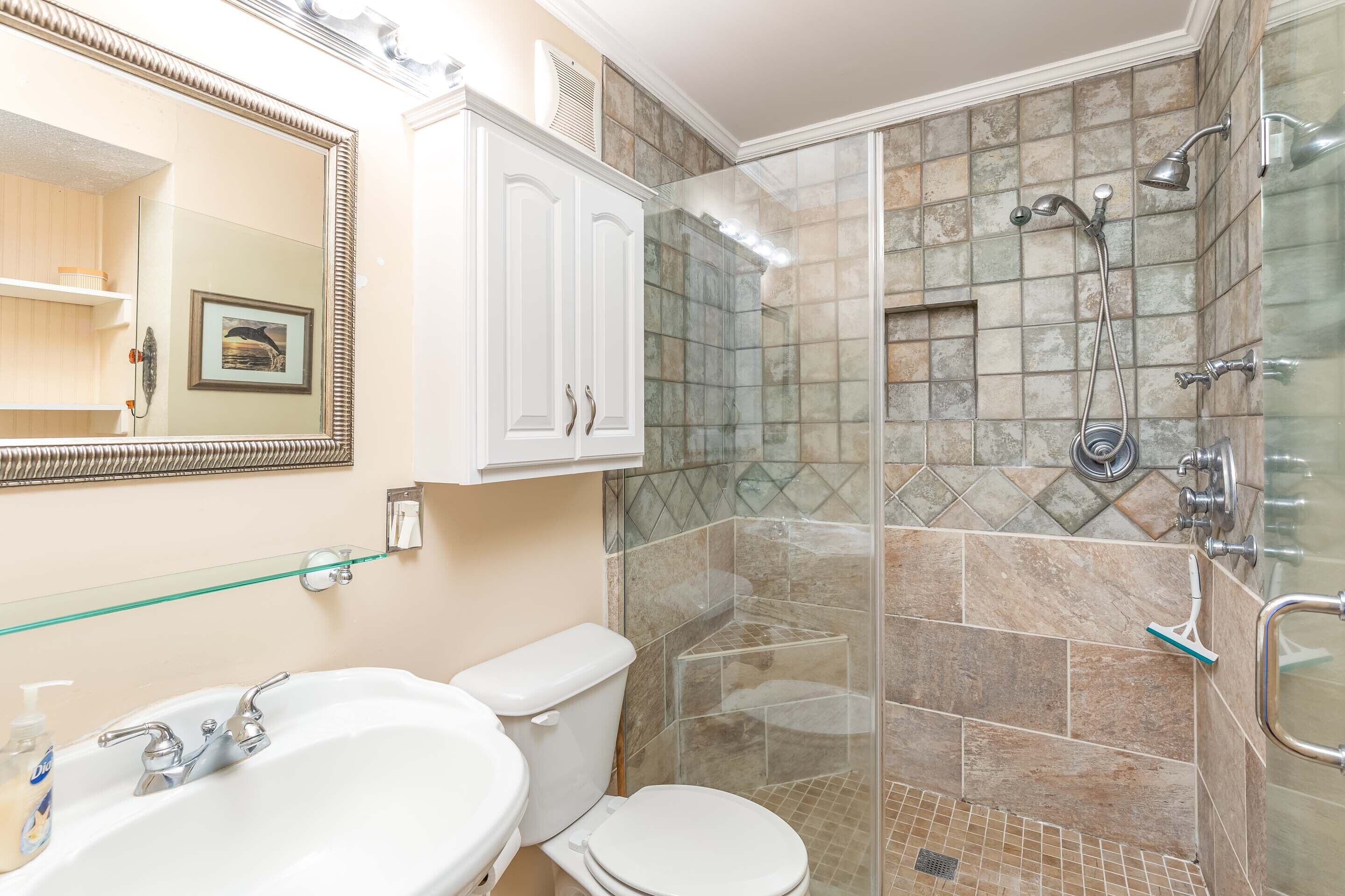 A bathroom with a glass-enclosed shower, a white sink, and a toilet.