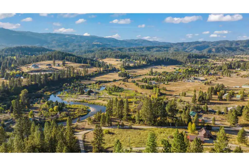 Un paysage rural avec une rivière, des maisons éparpillées et de vastes forêts.