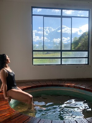 A person sitting by a window overlooking a landscape with trees and hills. - centro turístico ambiaku - Hostel (Colón)
