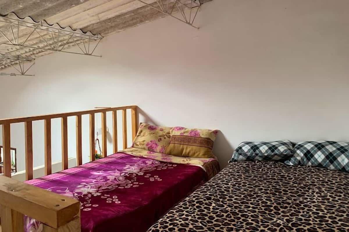 A bedroom with a wooden headboard, a bed with a purple floral bedspread, and a leopard print bedspread.