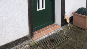 A green door with a white window, a black doorbell, and a potted plant beside it. - Casa del mar - casa 1 (Cuxhaven)