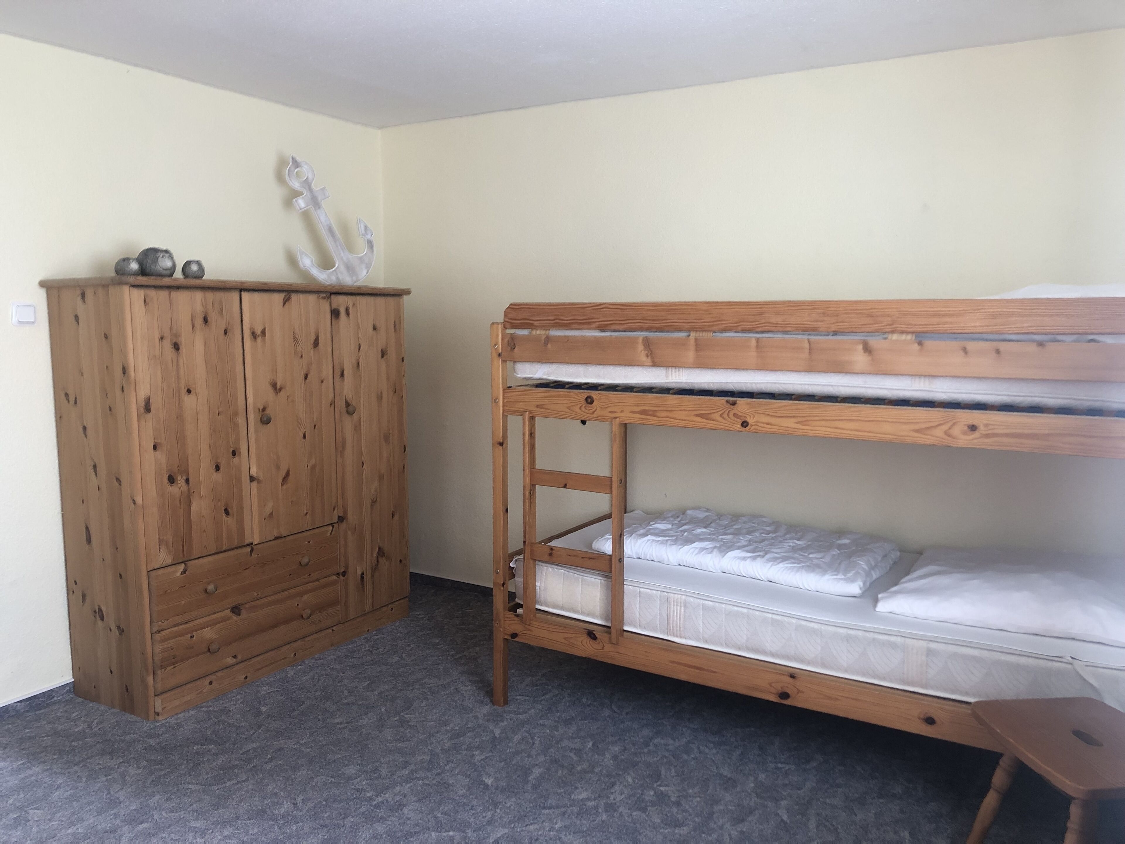 A bunk bed with a wooden frame and a dresser with drawers.