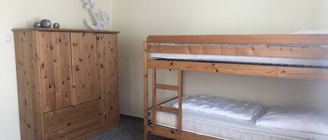 A bunk bed with a wooden frame and a dresser with drawers.