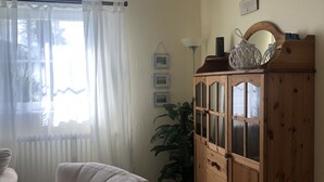 A living room with a beige sofa, a wooden cabinet, and a potted plant. - Casa del mar - casa 1 (Cuxhaven)