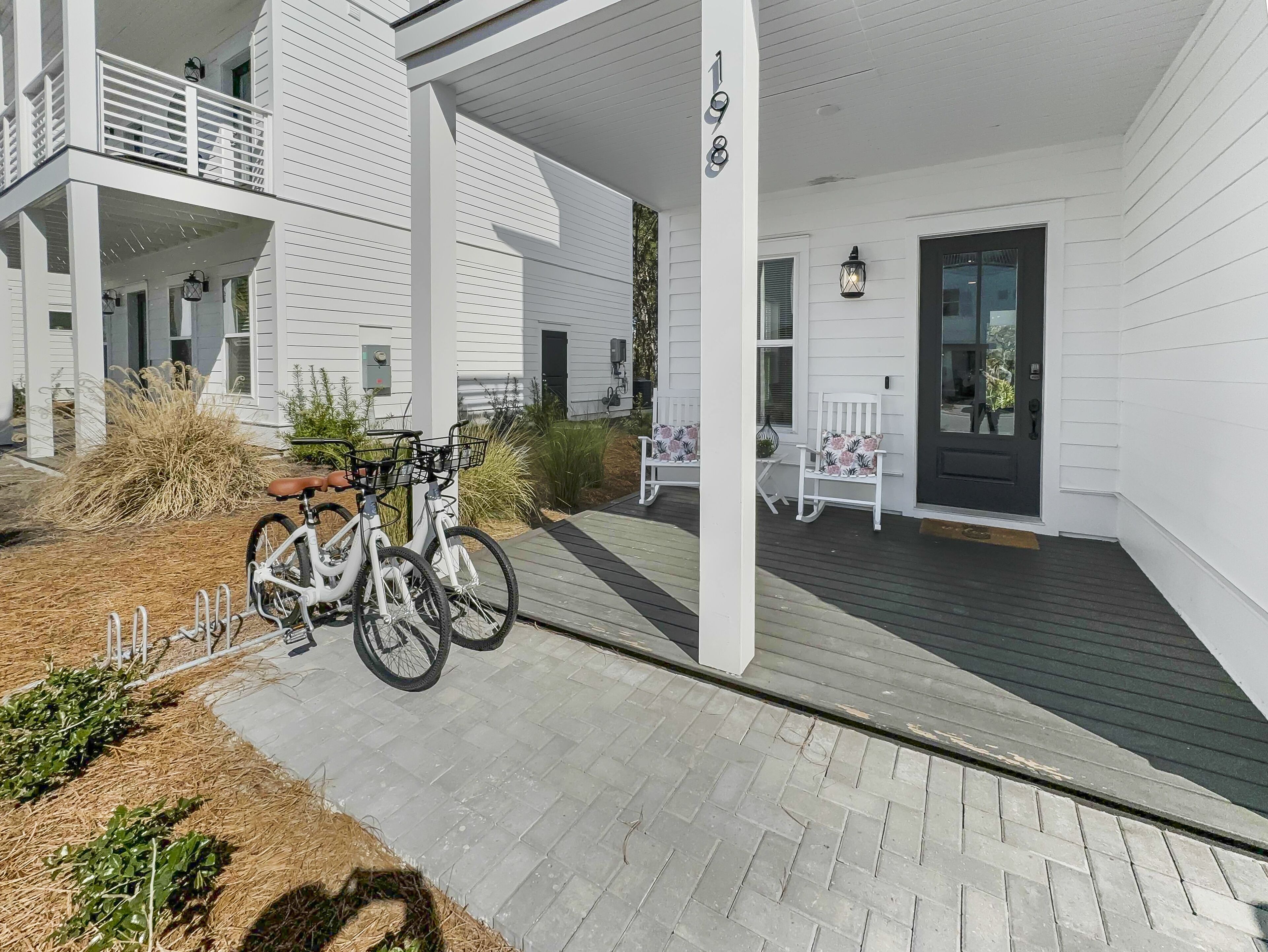 Een wit gebouw met een overdekte veranda, twee fietsen en tuinmeubilair.