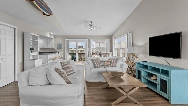 A spacious living room with a white sofa, a wooden coffee table, and a teal entertainment unit.