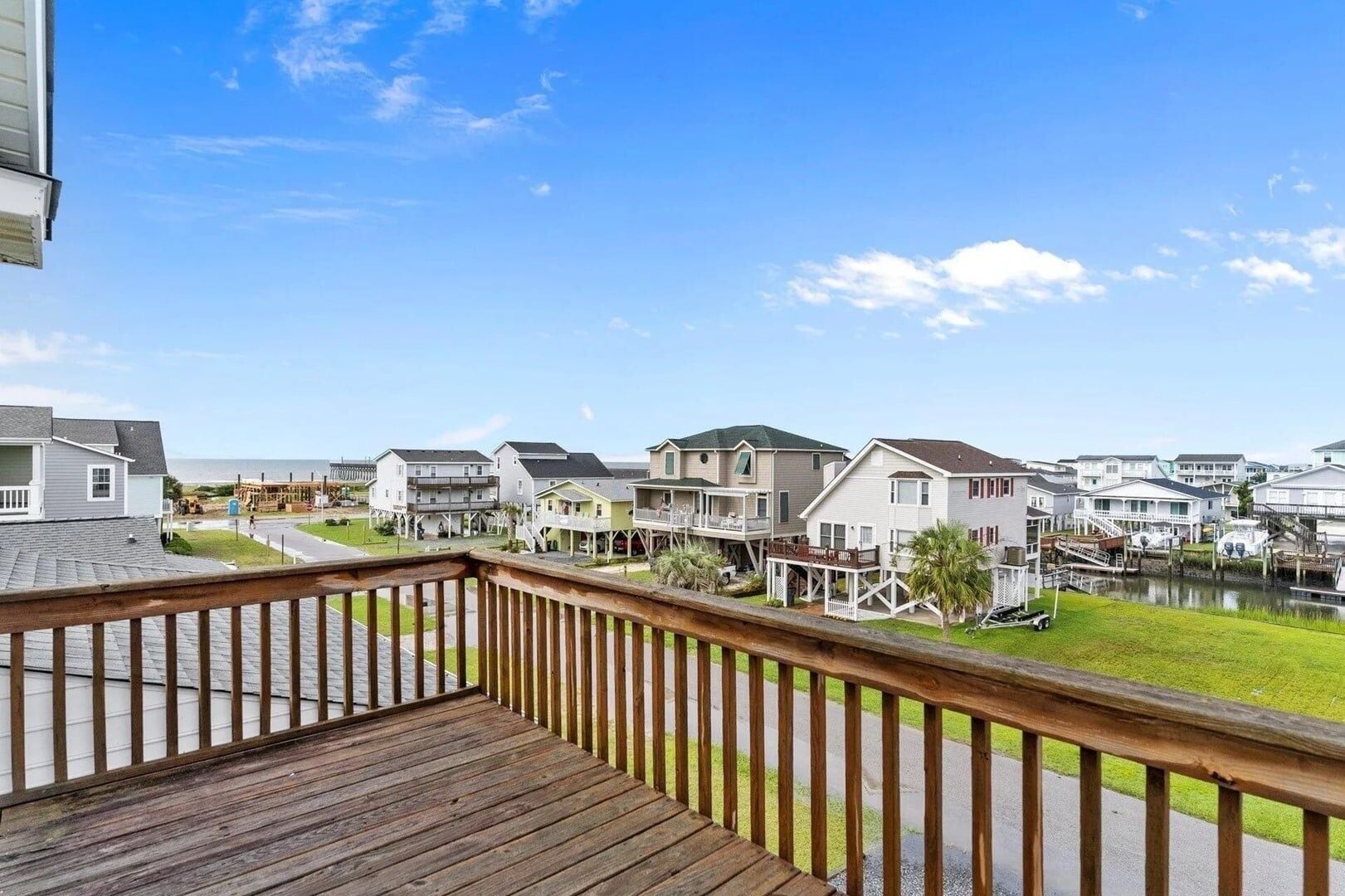 Une terrasse en bois offrant une vue sur un quartier riverain, avec ses maisons et son quai.