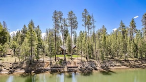 Un chalet au bord du lac, doté d’une terrasse en bois et offrant une vue dégagée sur la forêt environnante.