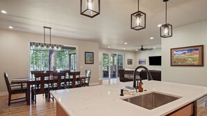 Une cuisine spacieuse dotée d’un grand îlot central, d’une table à manger en bois et de luminaires suspendus.