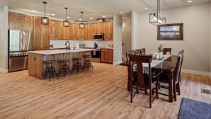 Une cuisine moderne avec des meubles en bois, des appareils électroménagers en acier inoxydable et un îlot central doté de tabourets de bar.