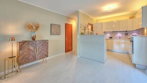 Une cuisine moderne avec des armoires blanches, un îlot central intégré et un luminaire suspendu.
