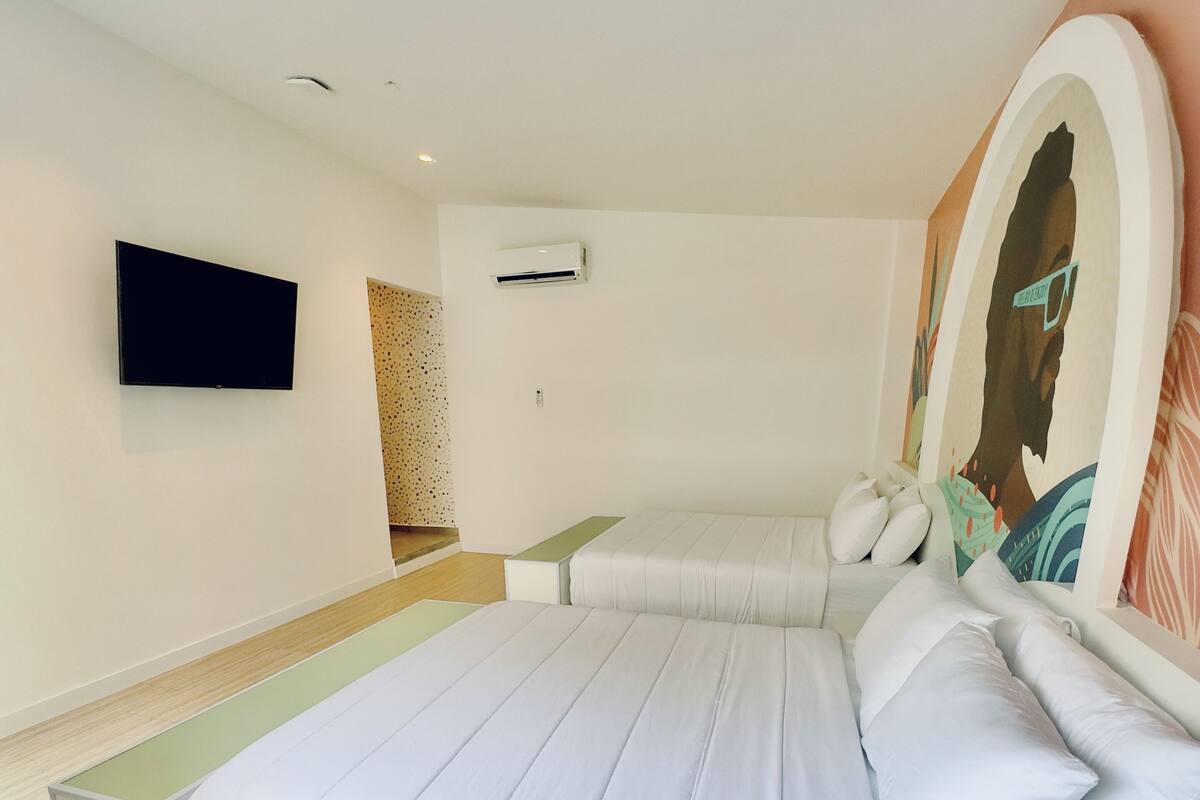 Un dormitorio moderno con una cama grande, un televisor de pantalla plana montado en la pared y un equipo de aire acondicionado.