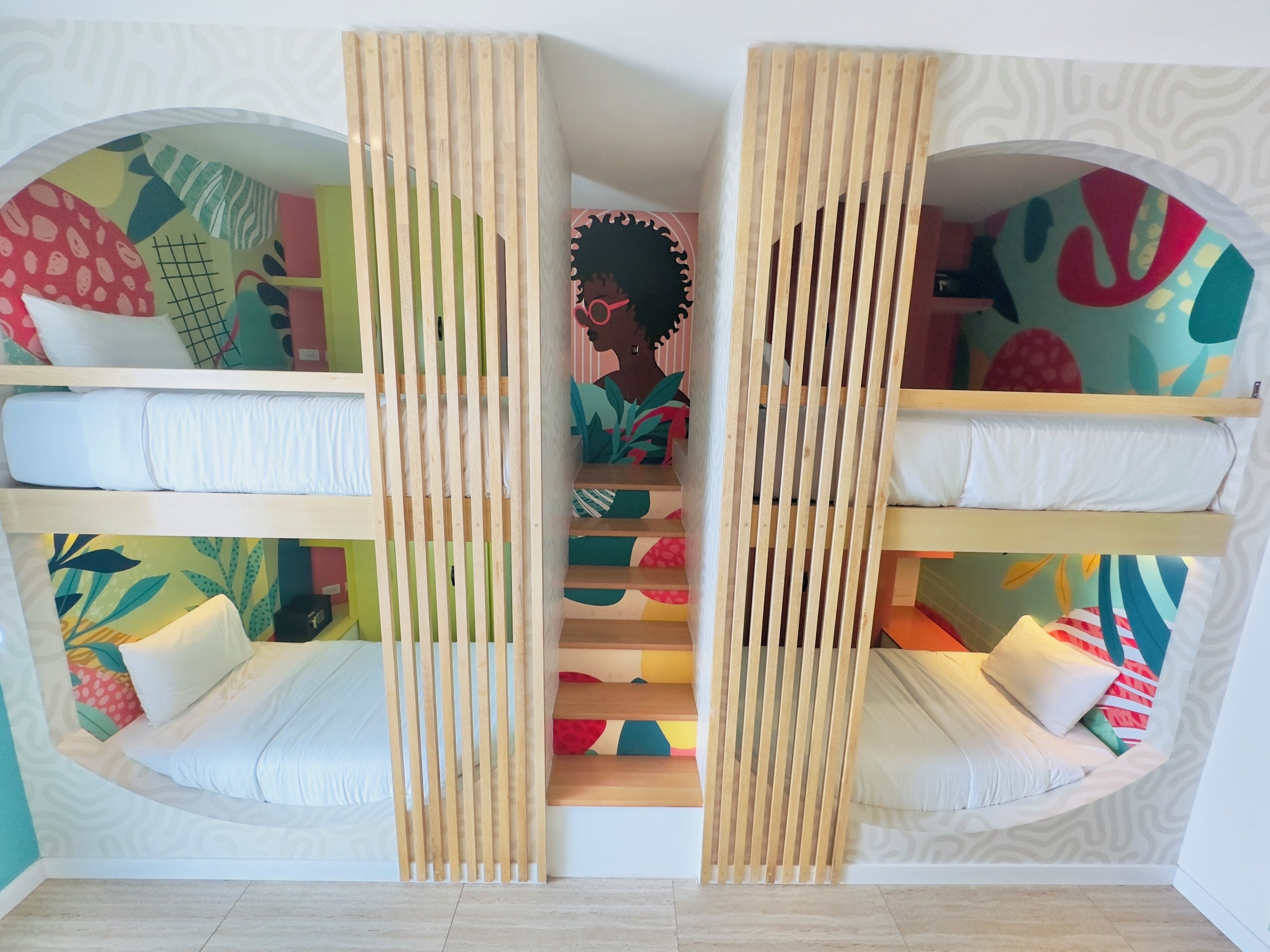 Una habitación con literas, una escalera y coloridas ilustraciones en las paredes.