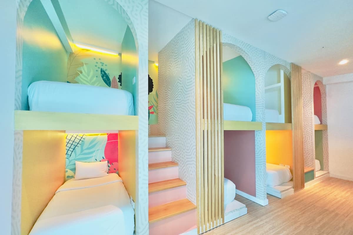 Una habitación de hotel moderna con literas, una escalera y un papel tapiz estampado.