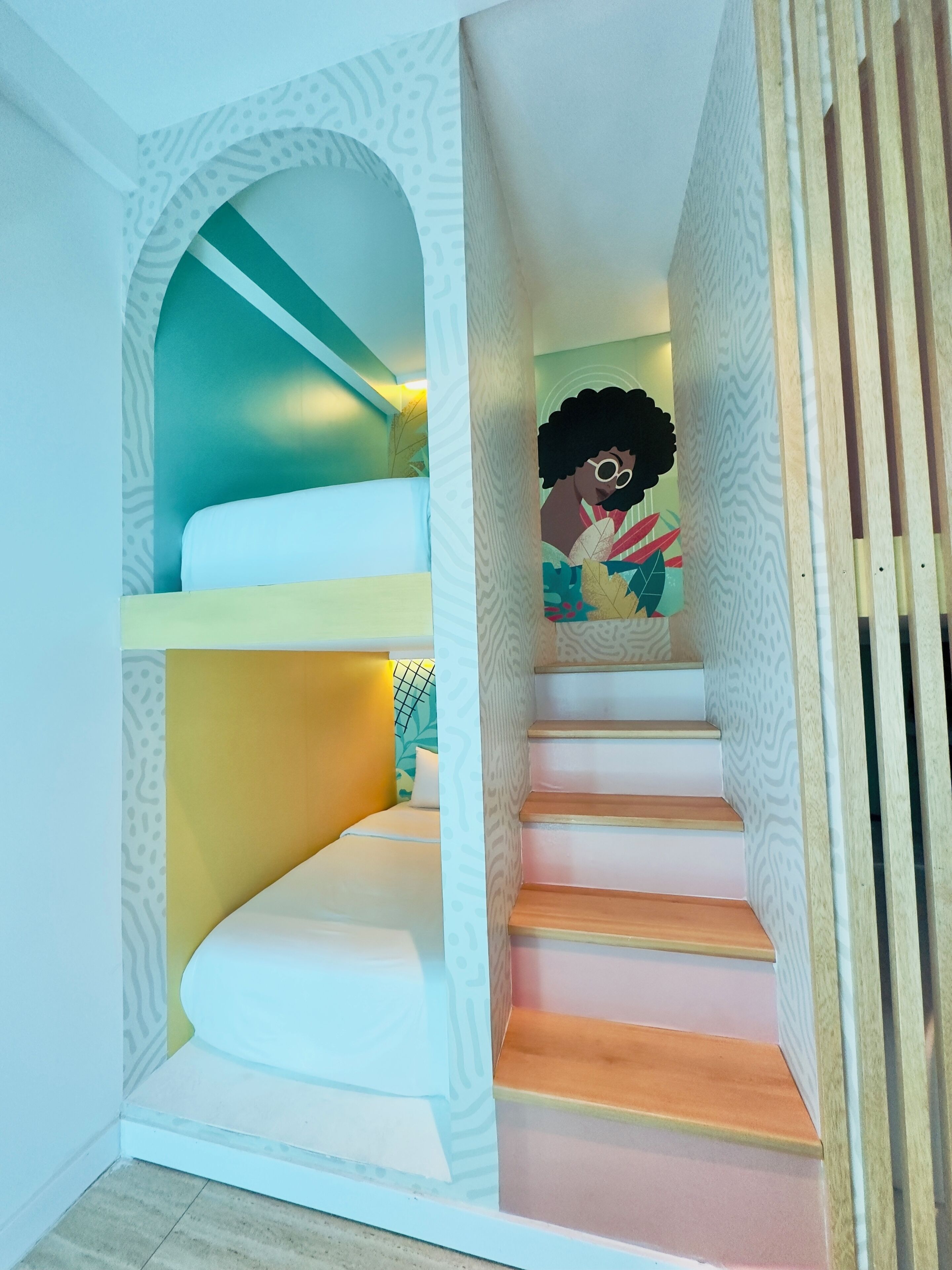 Una escalera de caracol con un diseño singular, que combina peldaños blancos, amarillos y de madera.
