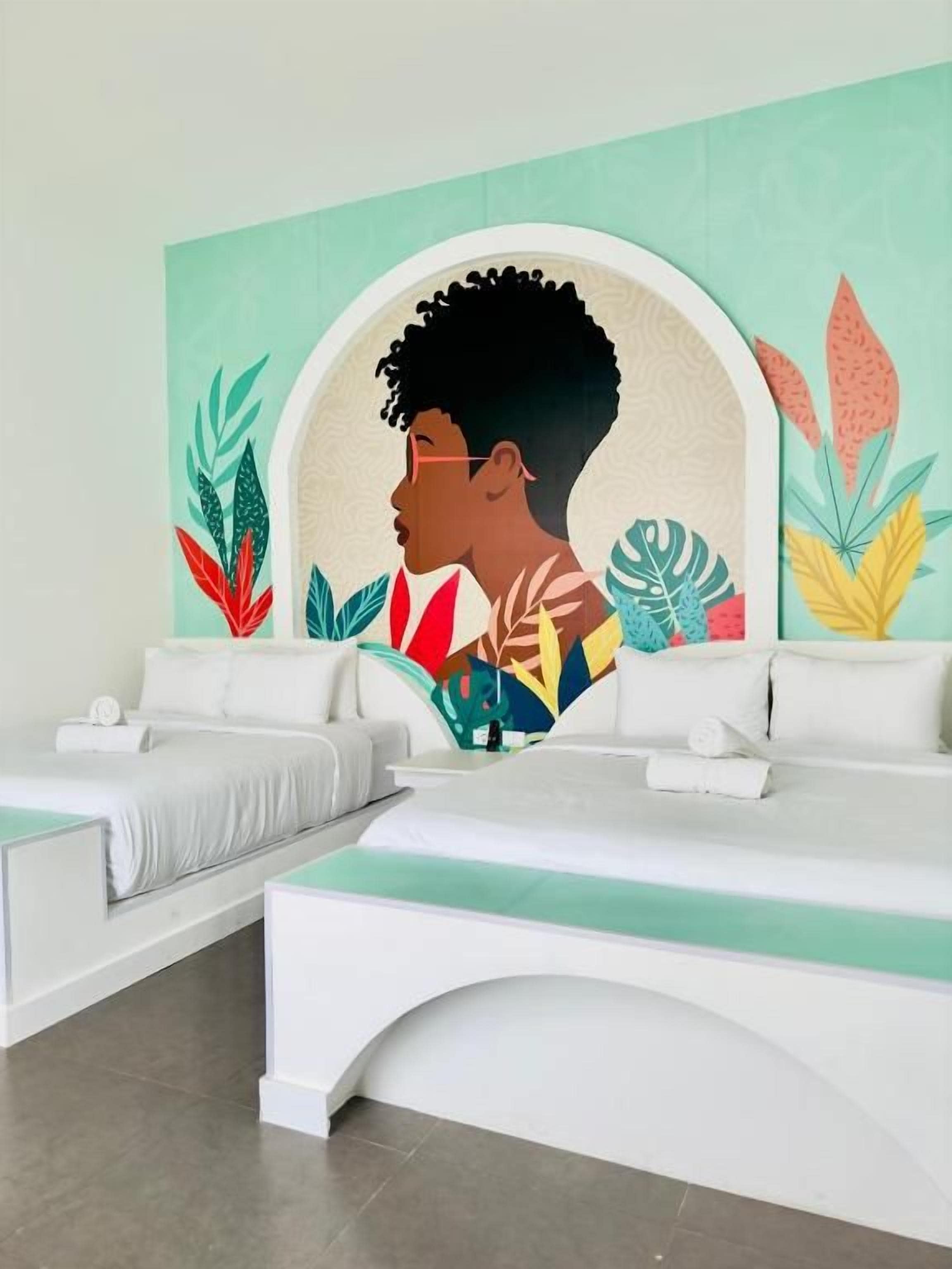 A hotel lobby with a large wall mural, a reception desk, and a seating area with white sofas.