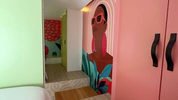 Una habitación de hotel moderna con una cama, un armario y un mural colorido en la pared.