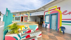 Un hostal con paredes exteriores de colores vivos, una piscina pequeña y una zona de recepción.