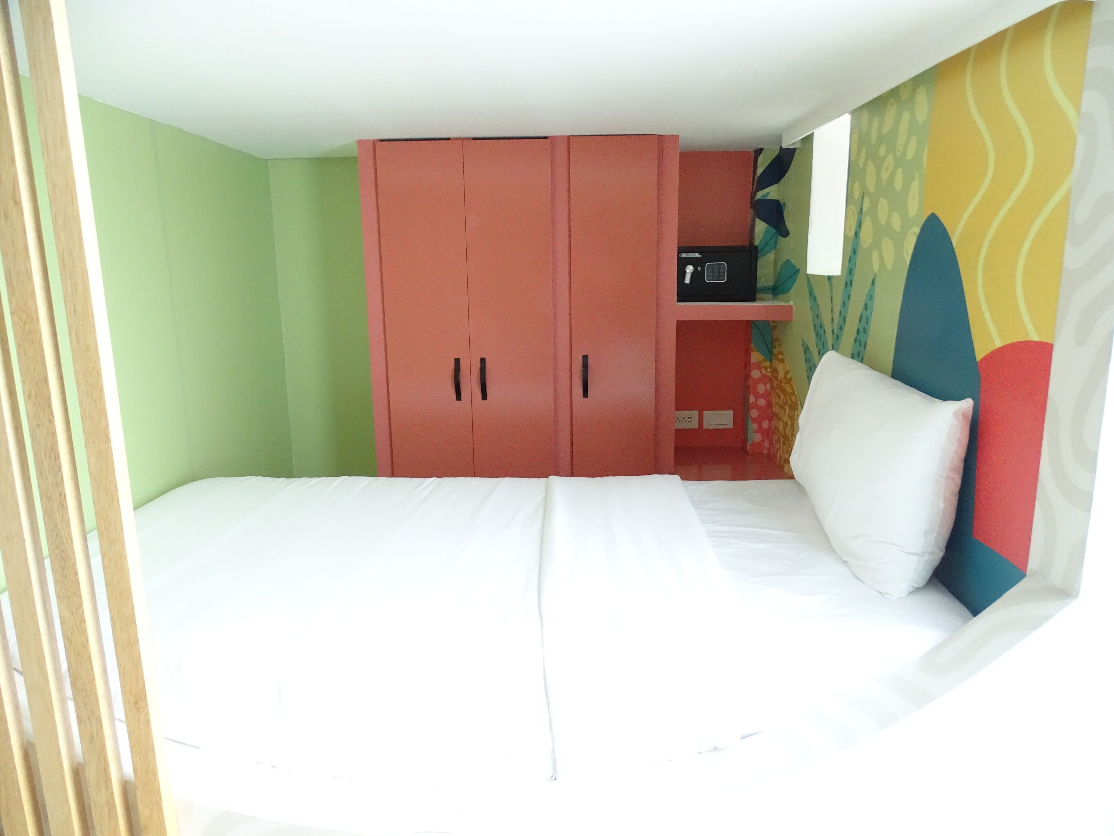 Un dormitorio con una cama, un armario y un pequeño estante con un objeto negro.