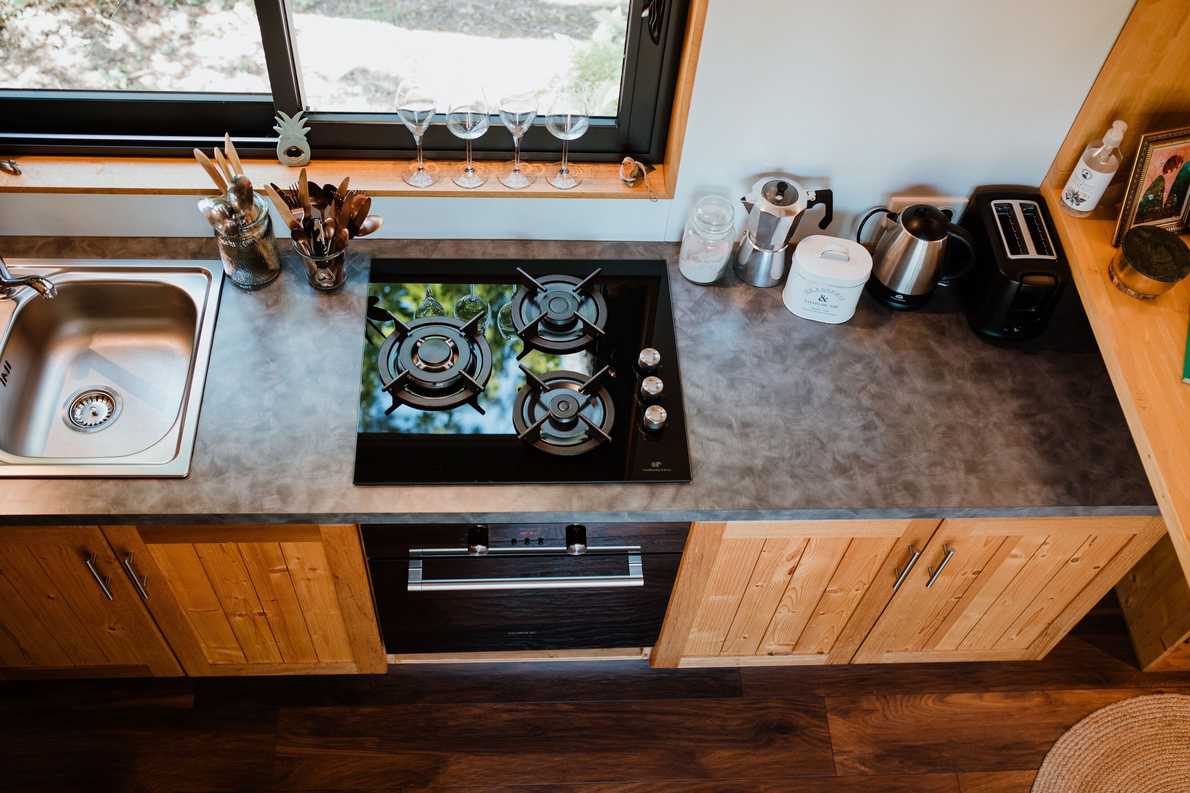 Una cocina con estufa, pileta y diferentes utensilios.