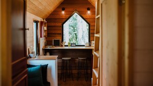 Una cocina acogedora con paredes de madera, un ventanal grande y dos taburetes de bar.