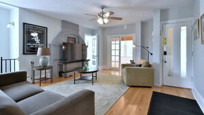 Un salon moderne avec une cheminée, un ventilateur de plafond et une grande fenêtre.