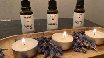 Trois bouteilles de Vitalis Sport Relax sont disposées sur un plateau en bois, accompagnées de bougies allumées et de fleurs de lavande.