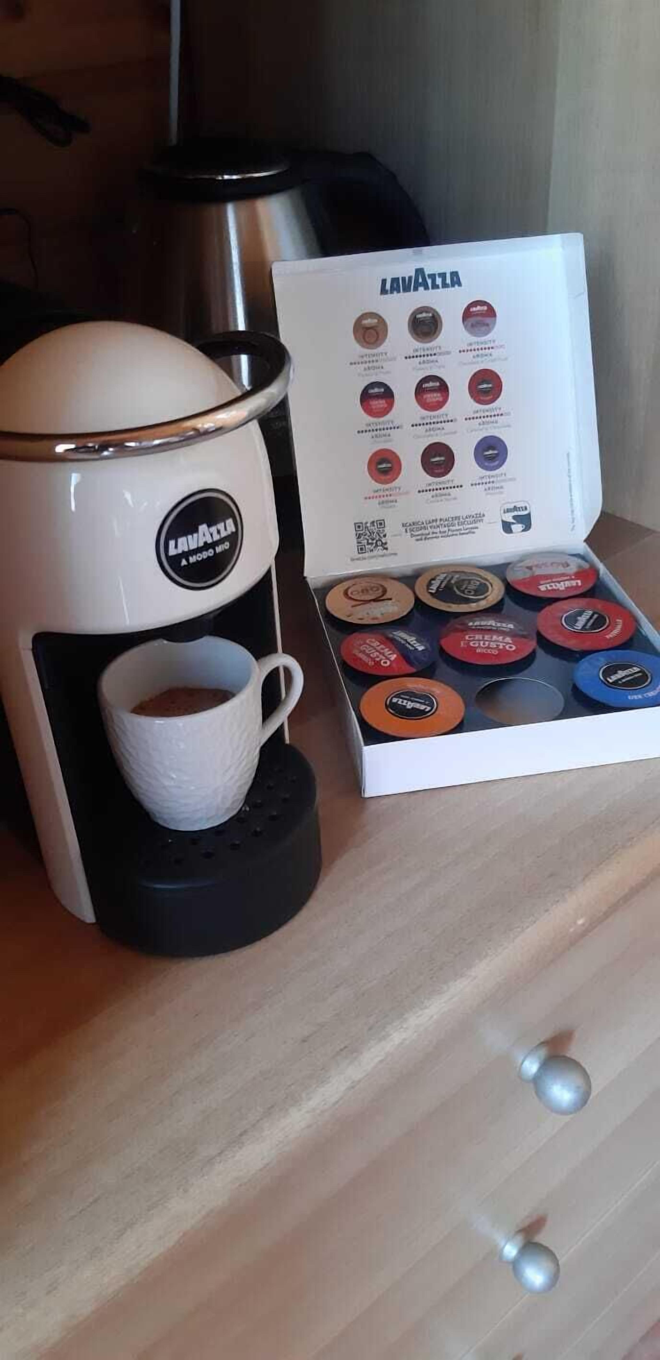 Eine Kaffeemaschine mit einer Tasse Kaffee, einer Kapselbox und einem Edelstahlkessel.