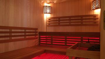A sauna with wooden benches and walls, and two wall-mounted light fixtures.