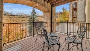 Un patio al aire libre techado con un arco de piedra, dos sillas de metal y una mesa.