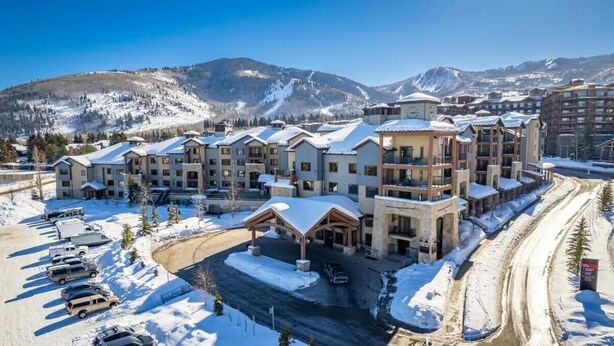 Un hotel de varios pisos con un patio central, rodeado de montañas nevadas.