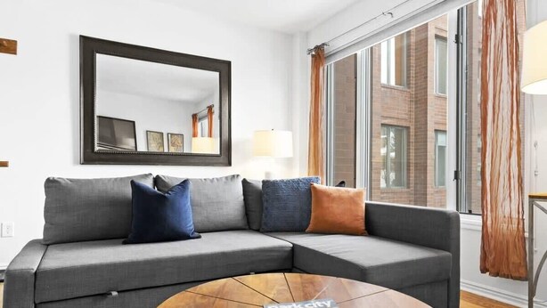 A modern living room with a grey sectional sofa, a round coffee table, and a large window with curtains. - One BDR In Heart of Park City! (Park City)