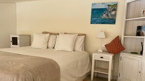 Un dormitorio ordenado con cama, mesitas de noche, lámpara, un cuadro y un armario.