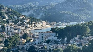 Un pueblo costero con edificios a lo largo de la colina y una playa a la distancia.