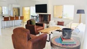 En moderne stue med sofa, stole, sofabord og fjernsyn.
