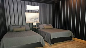 Una habitación con dos camas, aire acondicionado de pared y una pequeña mesa con lámpara.