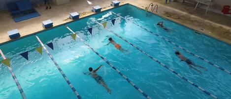 An indoor swimming pool with lanes marked by floating lane dividers and numbered starting blocks.