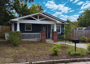A residential house with a front porch, a brick chimney, and a mailbox.