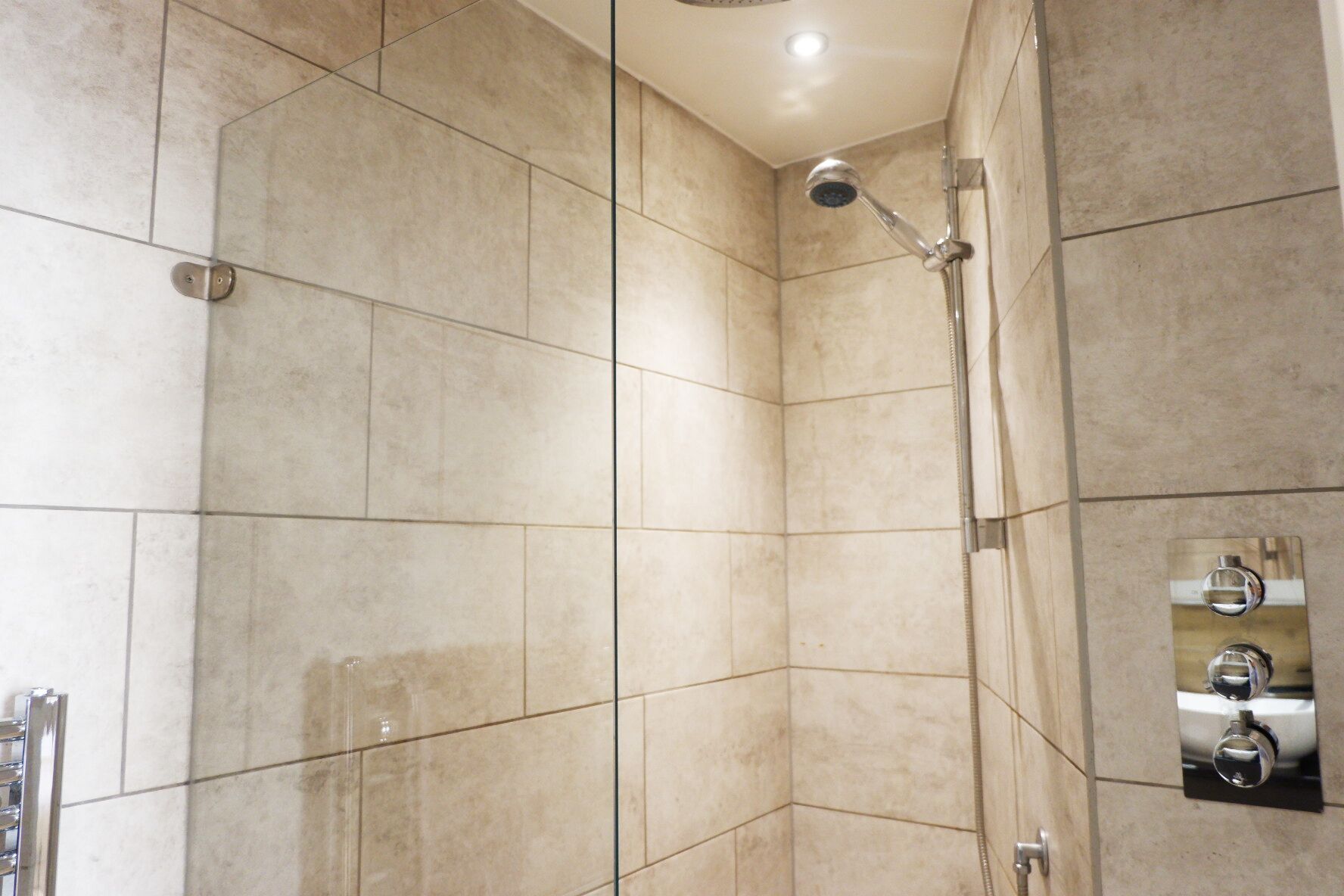 Una ducha moderna con cabezal de ducha manual y panel de control en la pared.
