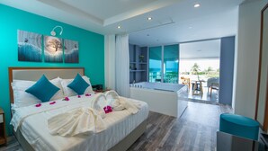 A modern hotel room with a large bed, a view of the balcony, and a bathroom with a bathtub. - Funplace Beach (Himmafushi)