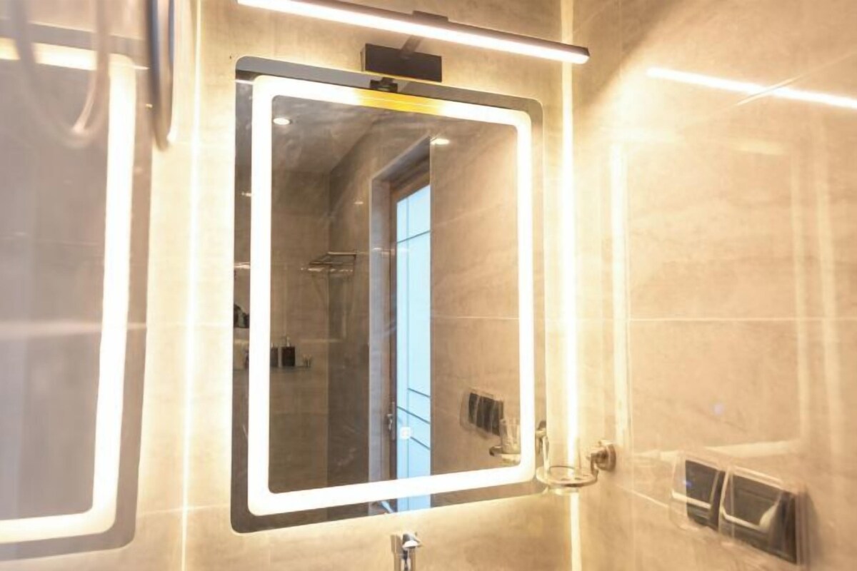 Un baño con un espejo grande, un lavabo y una ducha.