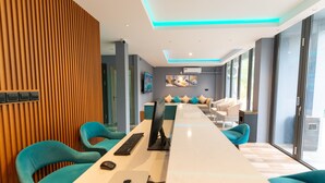 A modern conference room with a long table, blue chairs, and a computer setup. - Funplace Beach (Himmafushi)