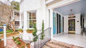 A white house with a front porch, a brick pathway, and a blue door. - The Jasmine Suite | Revisit History (Charleston)