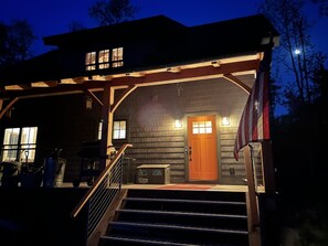 En træhytte med veranda, trapper og et amerikansk flag.