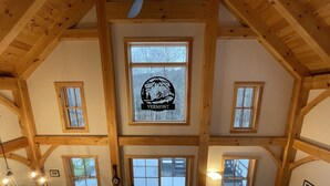 Amplia habitación estilo loft con techos altos, vigas de madera y ventanas grandes.