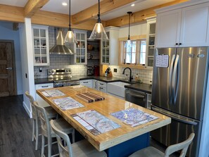 A modern kitchen with a central island, stainless steel appliances, and wooden accents.
