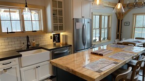 Una cocina moderna con armarios blancos, un refrigerador de acero inoxidable y una isla de madera con papeles.