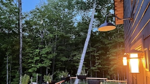 Terraza al aire libre con mobiliario de madera, incluyendo un sofá y sillones, rodeada por barandas de madera.